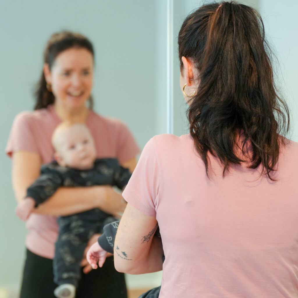 Kinderphysiotherapie-Zehlendorf, Therapie mit Babys und Neugeborenen. Claudia Liebig mit Baby vor einem Spiegel.